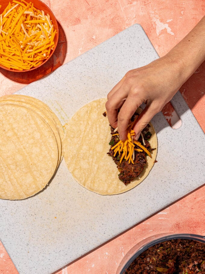 hand placing cheese on taco