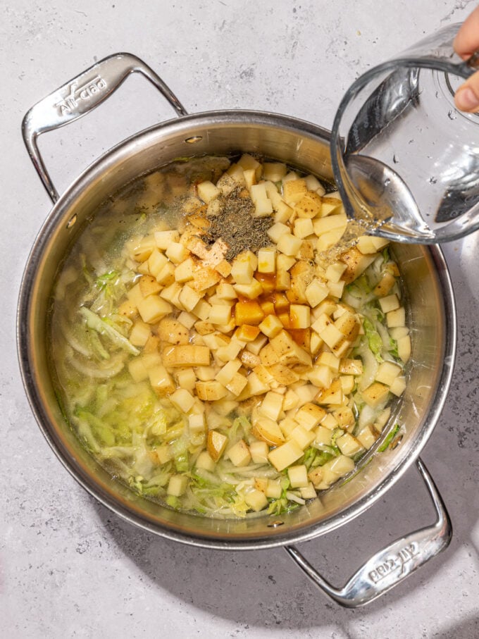 pouring water into pot with cabbage and potatoes