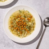 bowls of green cabbage soup with potato and chickpeas and spoon