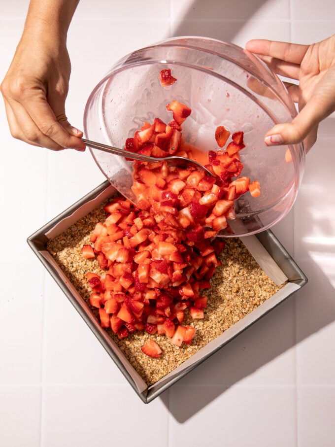 pouring strawberries over oatmeal bar base