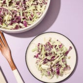 vegan coleslaw on plate with bowl and fork