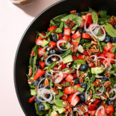 Spinach Salad with Fresh Blueberries and Strawberries in Black Bowl with Dressing