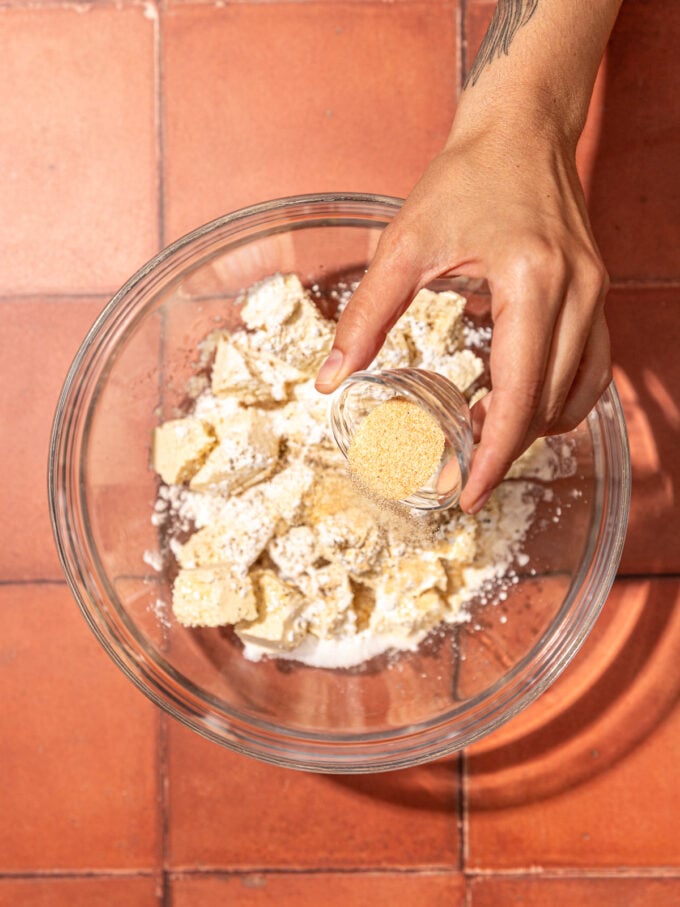 hand sprinkling garlic onto tofu