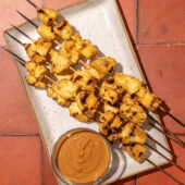 tofu skewers on white plate with peanut sauce