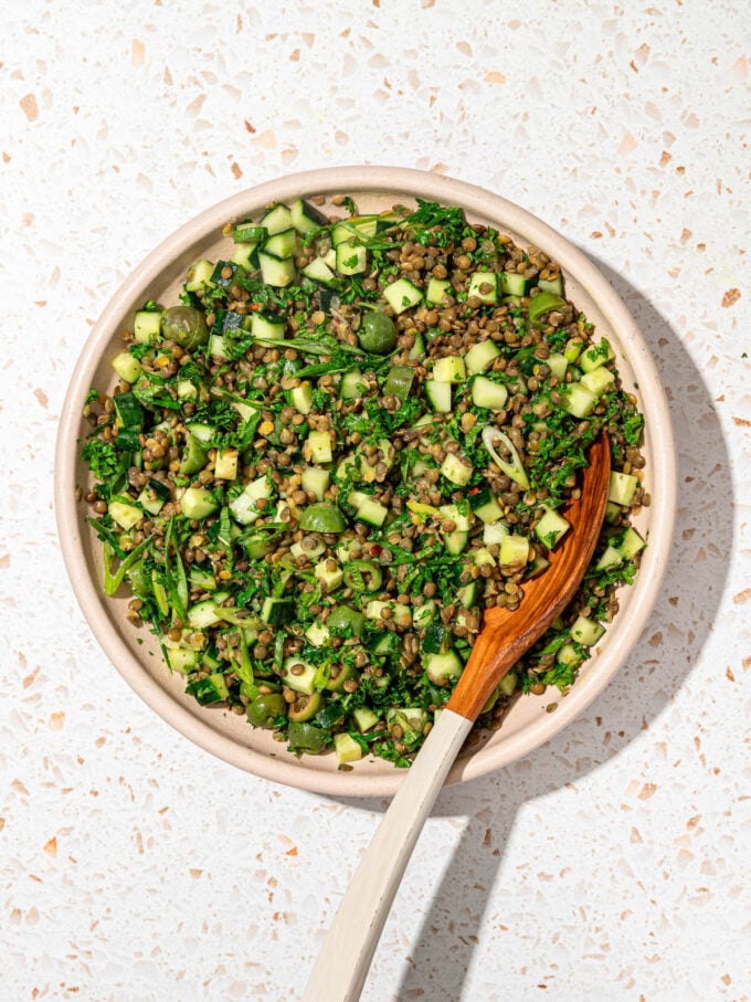 lentil salad with herbs in bowl with wooden spoon