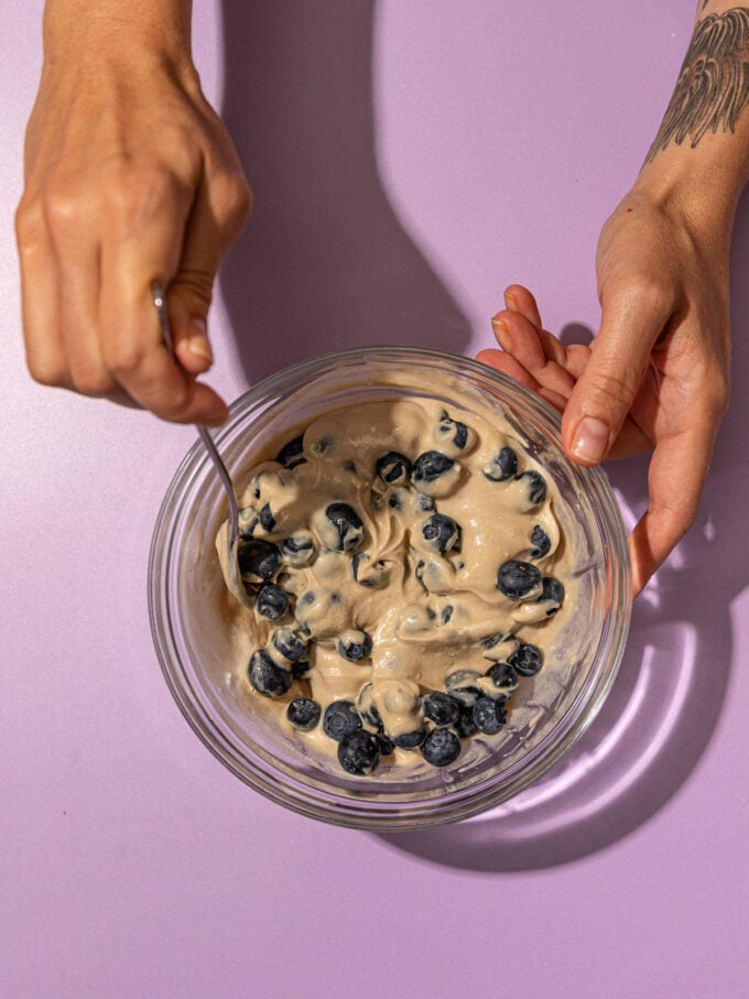 hand stirring blueberries into tahini yogurt