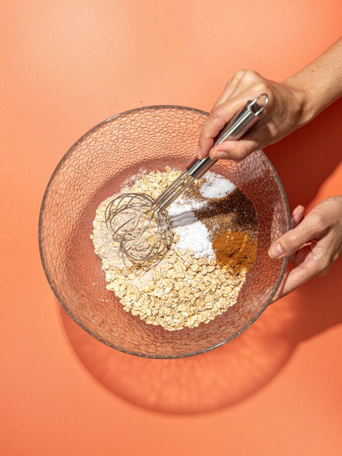 hand whisking flour and oats in bowl