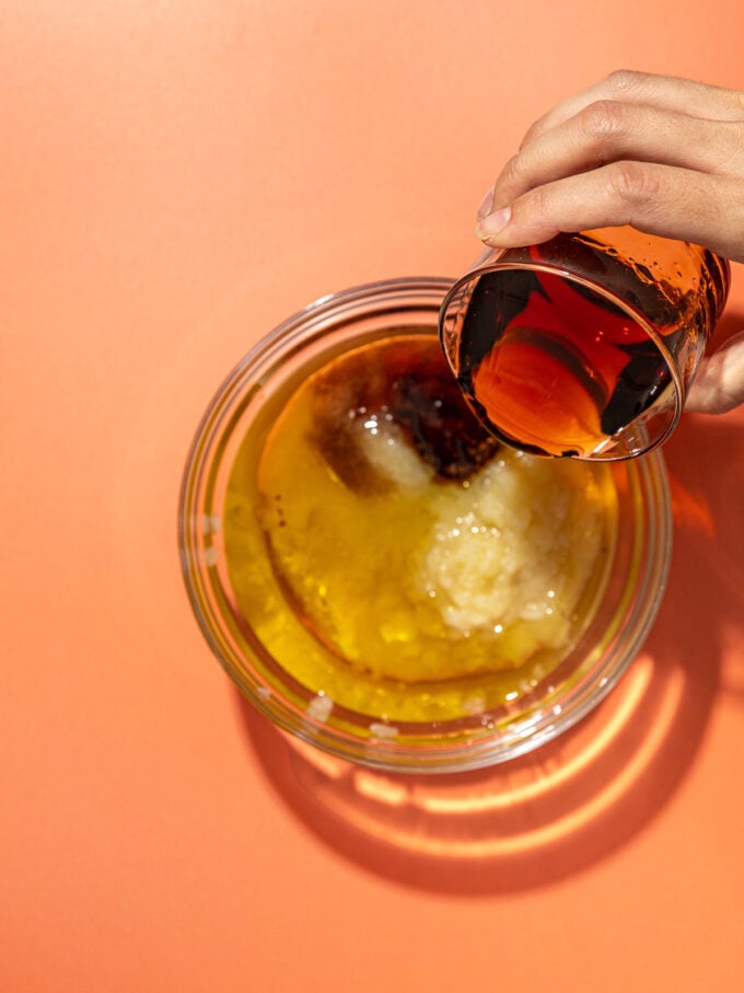 hand pouring maple syrup into applesauce