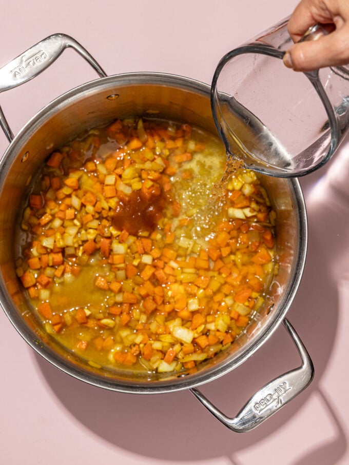 hand pouring water into soup pot