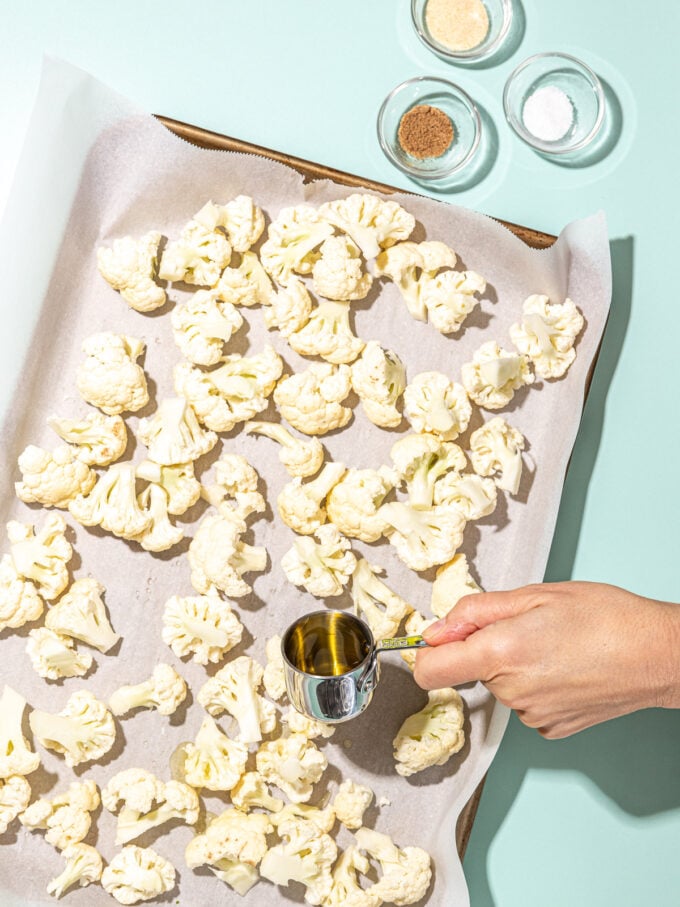 hand pouring oil over the cauliflower