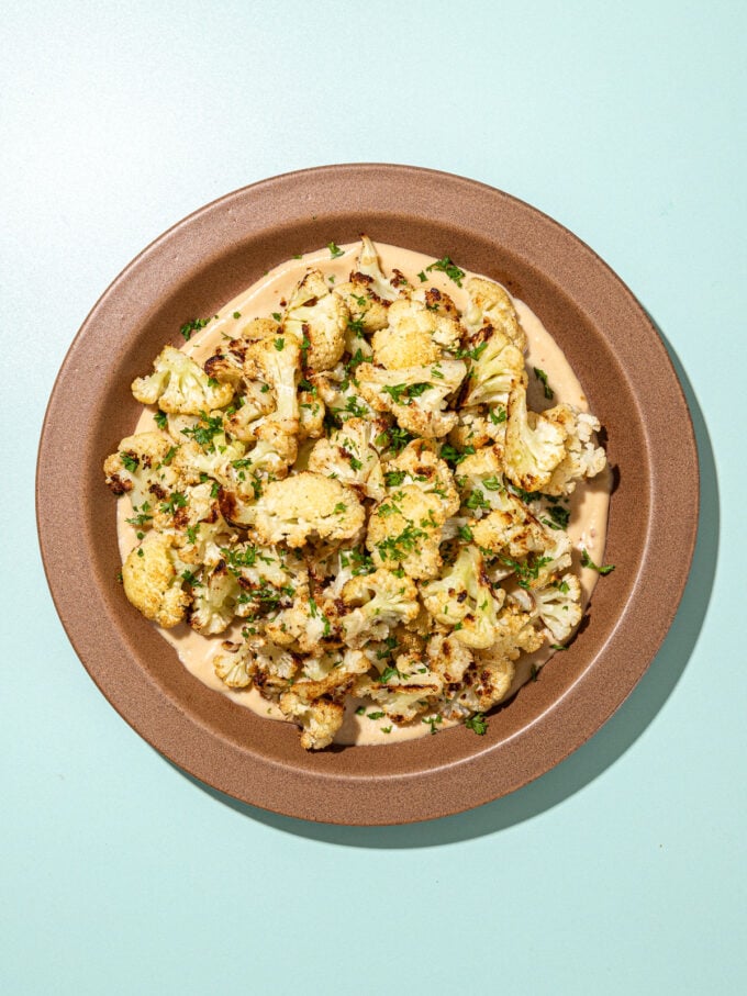 roasted cauliflower with tahini sauce on brown plate