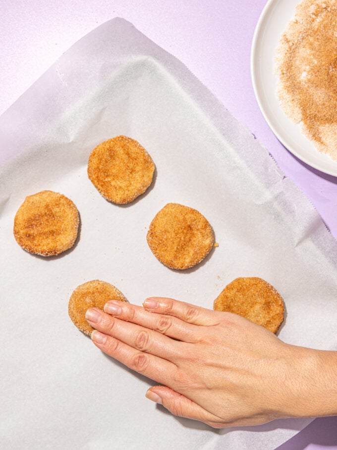 hand pressing snickerdoodle cookie