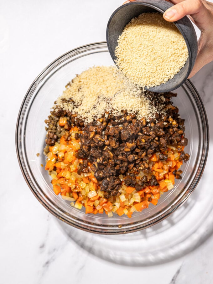 hand pouring panko into mushrooms