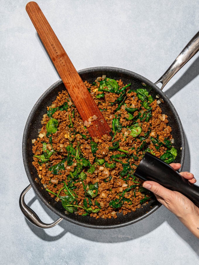 hand cracking pepper into veggie ground