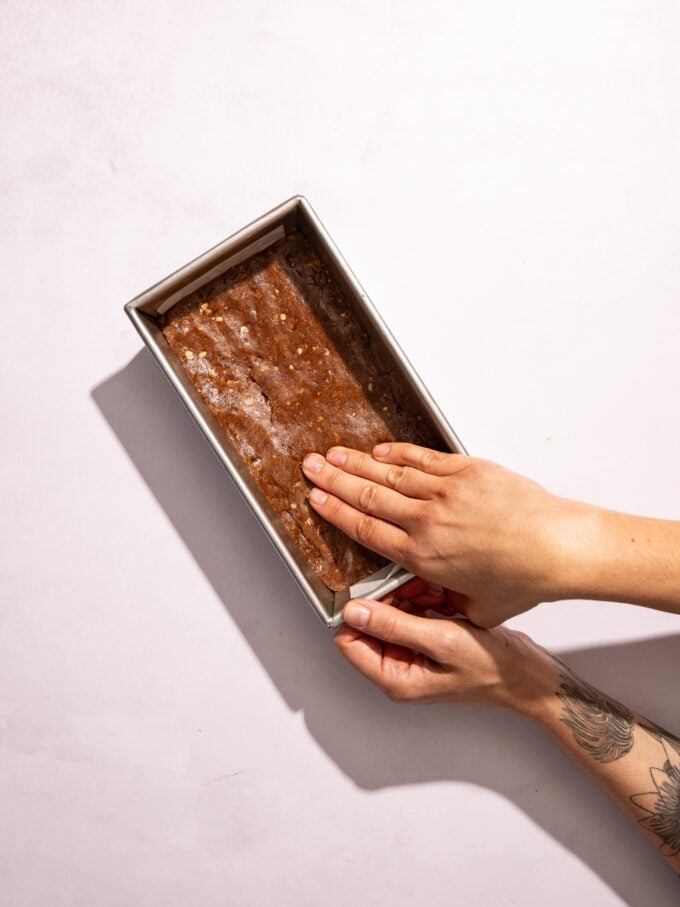 hand pressing chocolate dough into pan