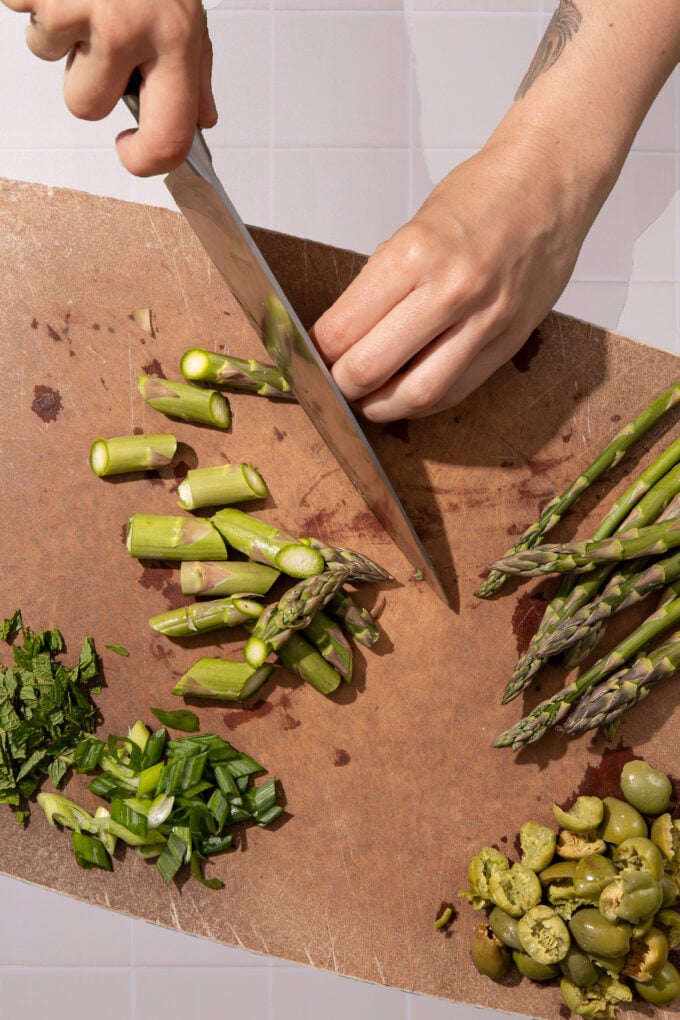 hand chopping asparagus on cutting board