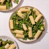 white plates with pasta, peas and asparagus
