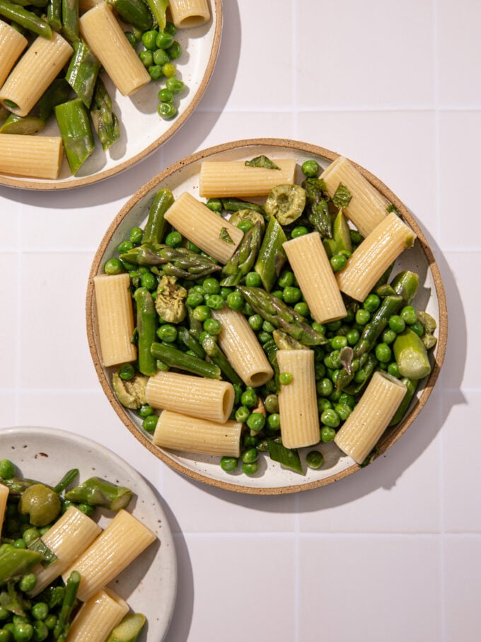 white plates with pasta, peas and asparagus
