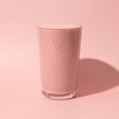 pink smoothie in glass on pink background