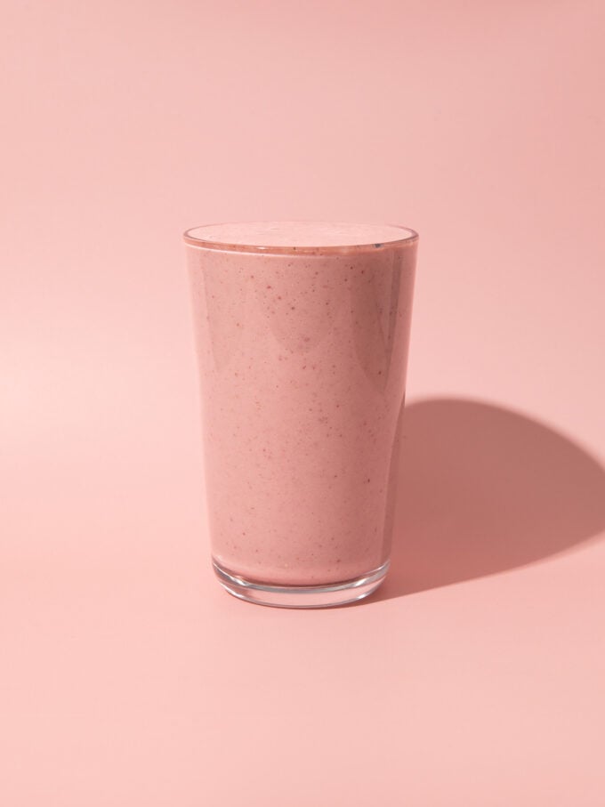 pink smoothie in glass on pink background
