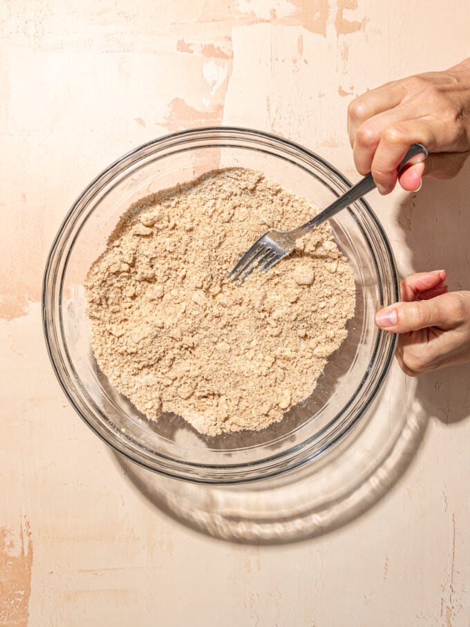 hand mixing butter and flour in glass bowl