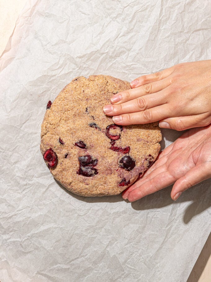 hand pressing disk of cherry dough