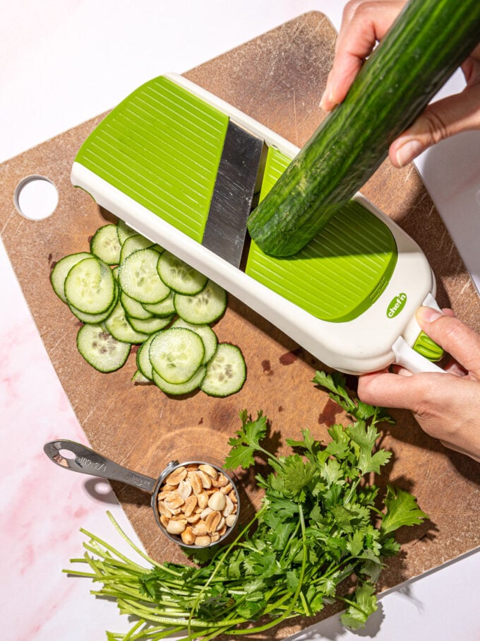 hand slicing cucumber on mandolin