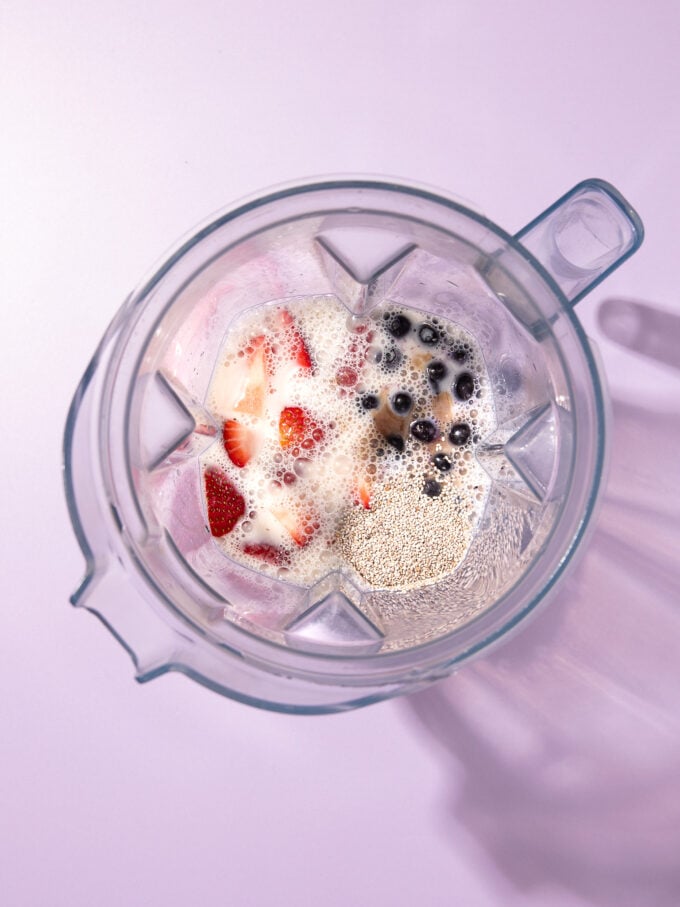 strawberries, blueberries and milk in a blender