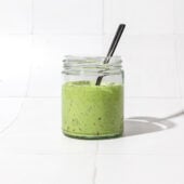 creamy green dressing in glass jar with black spoon
