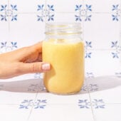 hand holding mason jar of smoothie on tile background