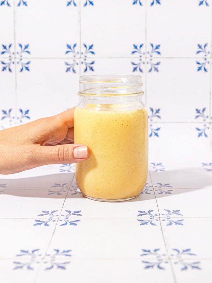 hand holding mason jar of smoothie on tile background
