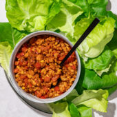 crumbled tempeh in bowl with black spoon and lettuce leaves