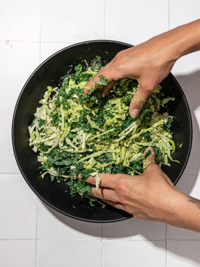 hand massaging kale cabbage salad