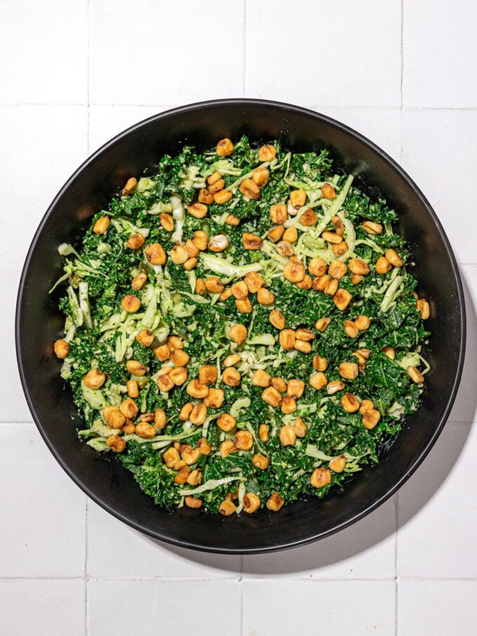 kale and cabbage salad with corn nuts in black bowl