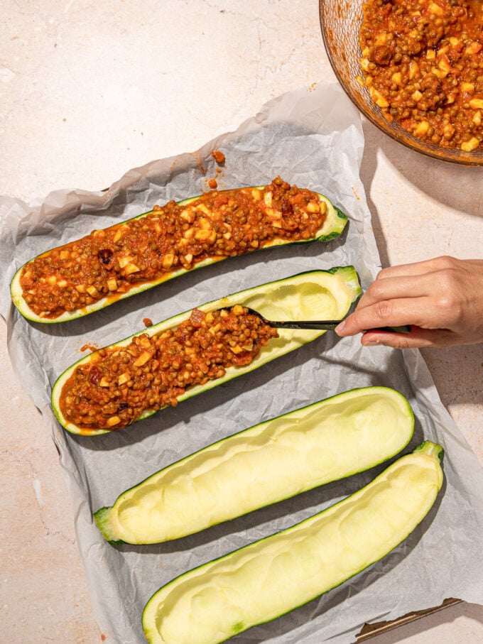 hand stuffing zucchini with lentil sauce