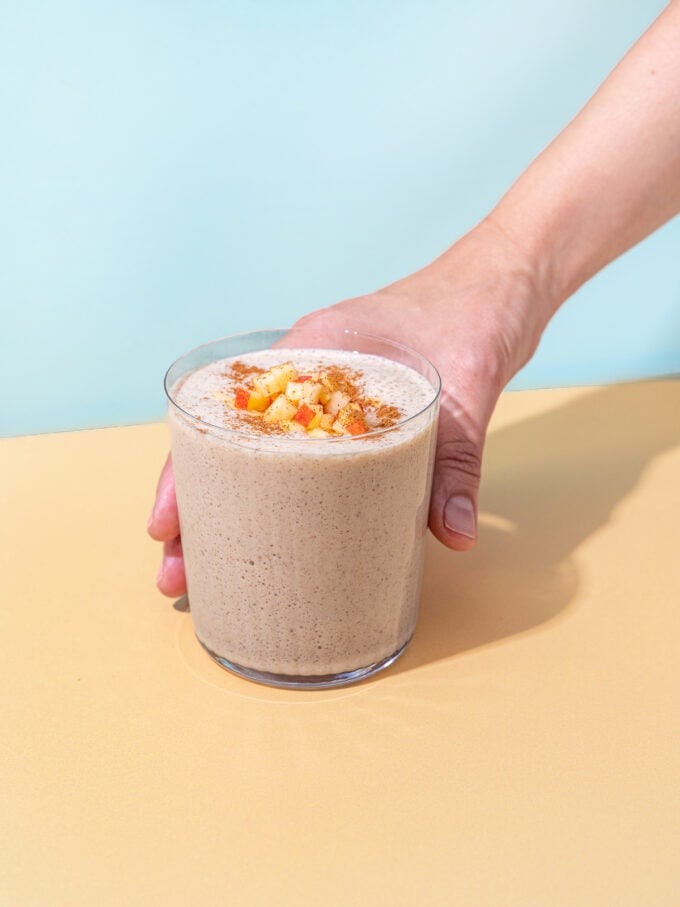 hand holding apple smoothie in glass