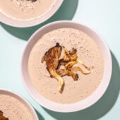 white bowls of mushroom soup on mint coloured background
