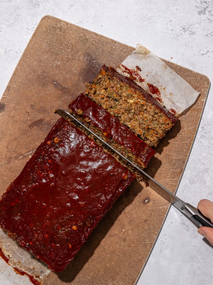 hand slicing lentil loaf on cutting board