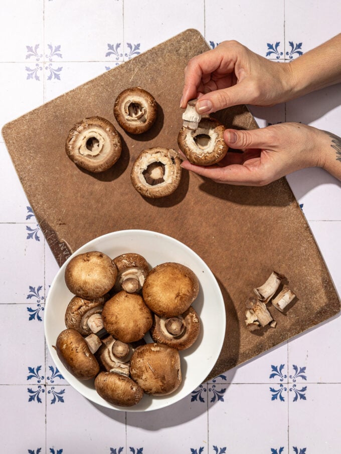 hand plucking stem out of mushrooms on cutting board