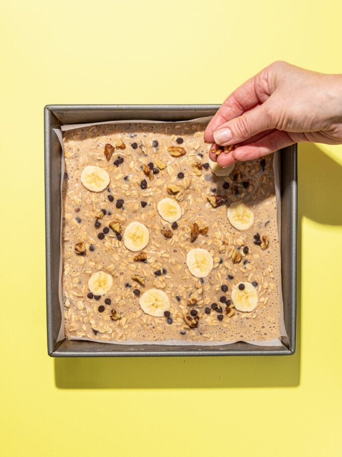 hand adding chocolate chips to banana baked oats