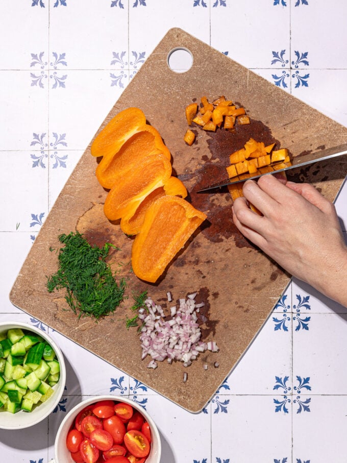hand chopping orange peppers