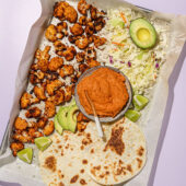 roasted cauliflower, tortillas, cheese, avocado and chipotle sauce on baking sheet