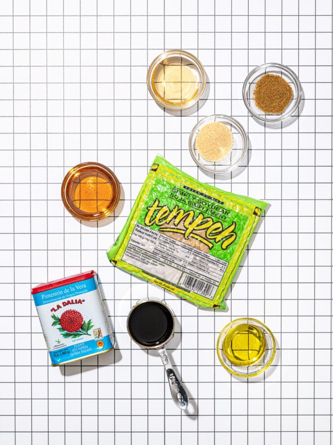 package of tempeh, smoked paprika with bowls of cumin, maple syrup, oil and soy sauce