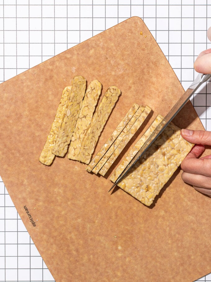 hand slicing tempeh into strips with knife